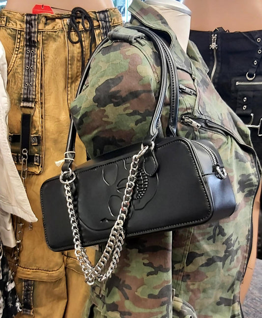Skull embossed barrel handbag with chain accessory.